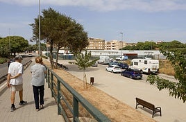 Dos viandantes pasean por un jardín de Alfafar.