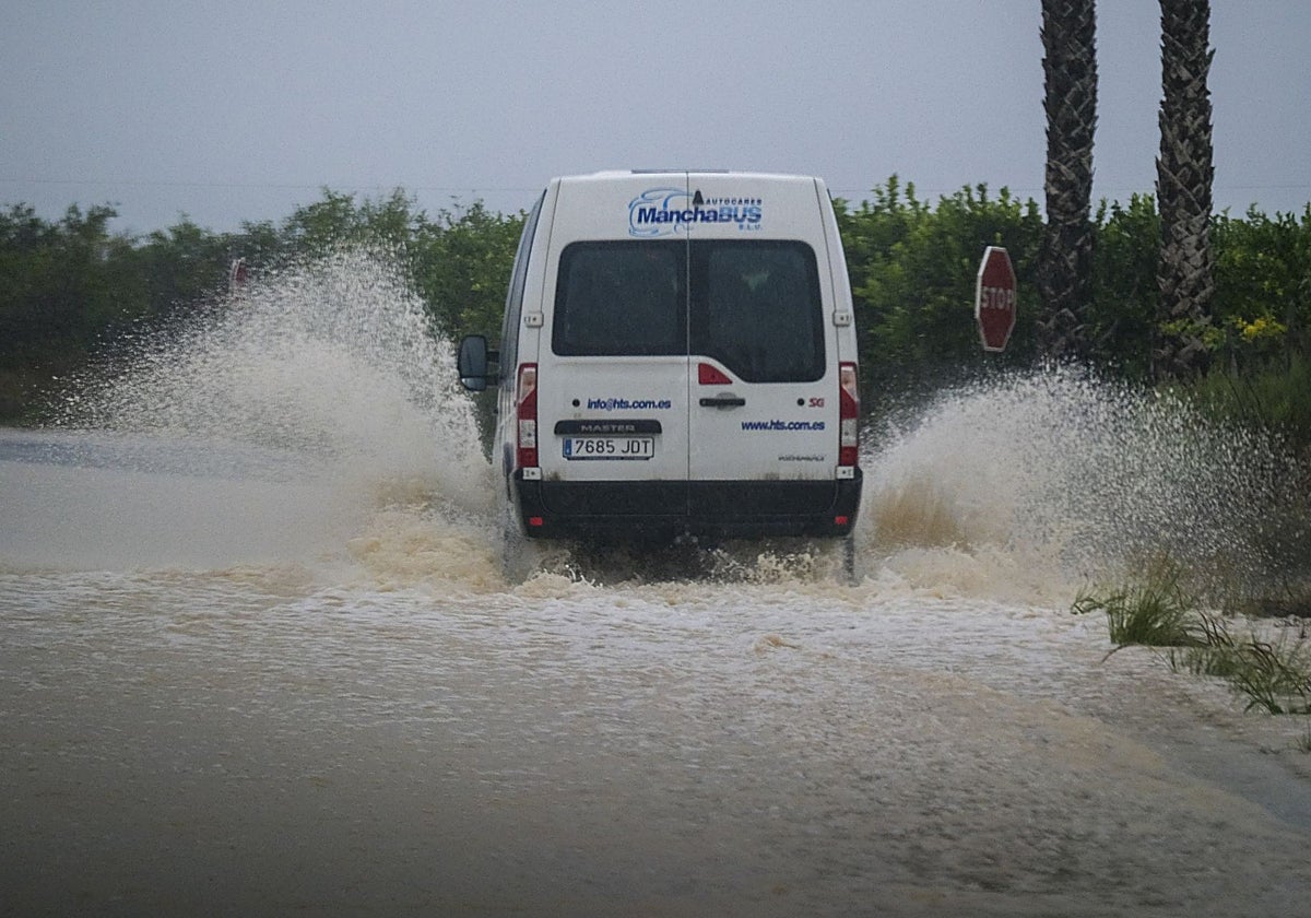 Un vehículo circula por una carretera anegada.