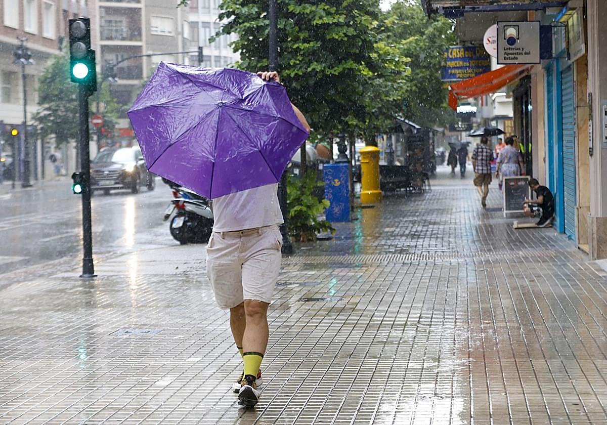 Un hombre se resguarda de la lluvia en Valencia. Imagen de archivo.