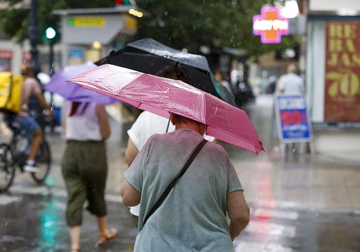 Una mujer se resguarda de las lluvias en Valencia, en una imagen de archivo.