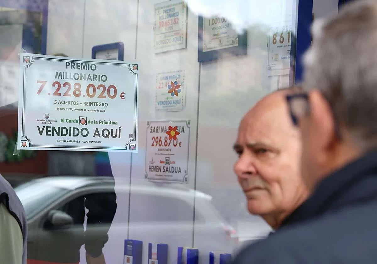 Una administración de Loterías y Apuestas del Estado cuelga el cartel de un premio.