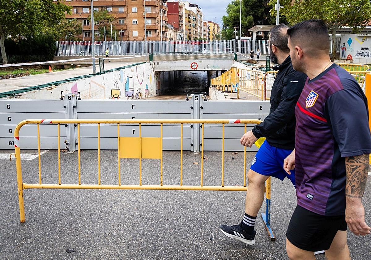 Dos vecinos pasan junto al paso inferior de Aldaia protegido contra las inundaciones.