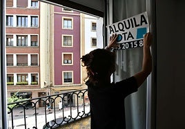 Una agente inmobiliaria coloca un cartel de 'se alquila' en un piso, imagen de archivo.