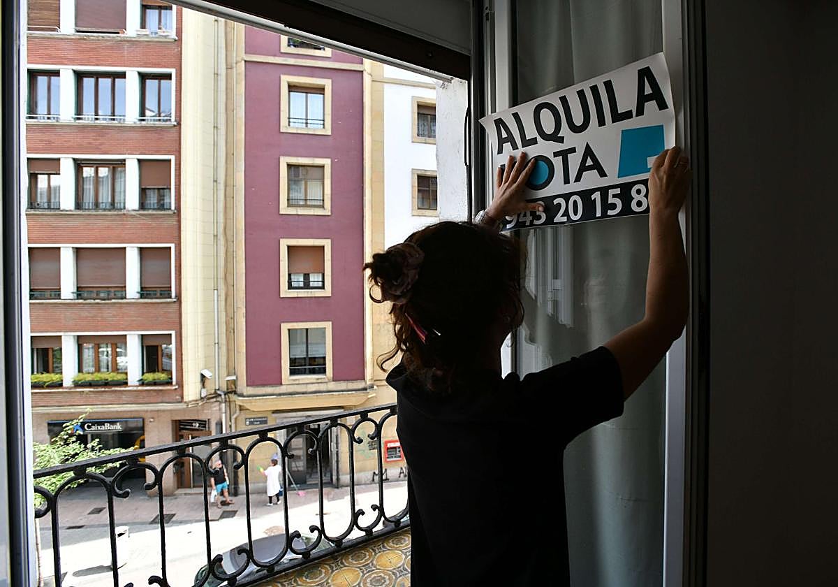 Una agente inmobiliaria coloca un cartel de 'se alquila' en un piso, imagen de archivo.