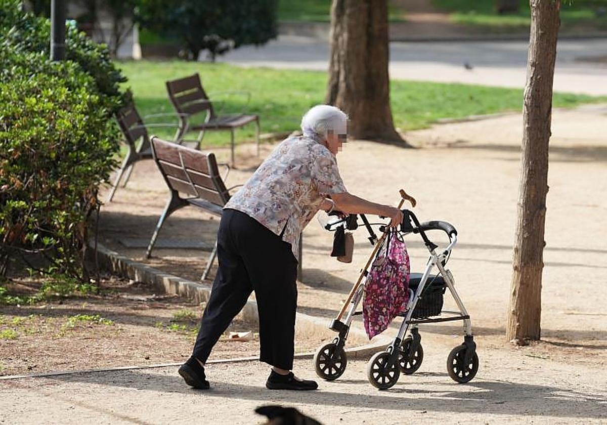Una mujer camina con un andador por un parque, en una imagen de archivo.