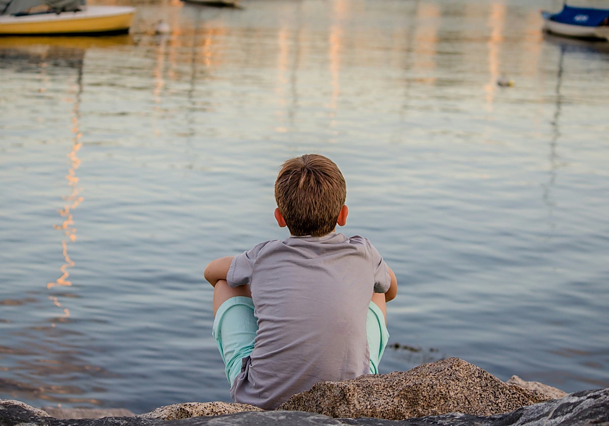 Un niño contempla el mar a solas desde unas rocas, en una imagen de archivo.