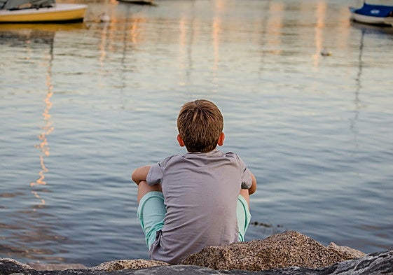 Un niño contempla el mar a solas desde unas rocas, en una imagen de archivo.