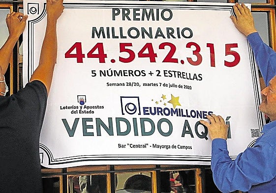 Dos ganadores de un premio de Euromillones cuelgan un cartel. Imagen de archivo.