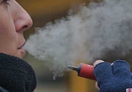 Una joven, con un váper en el exterior de un instituto.