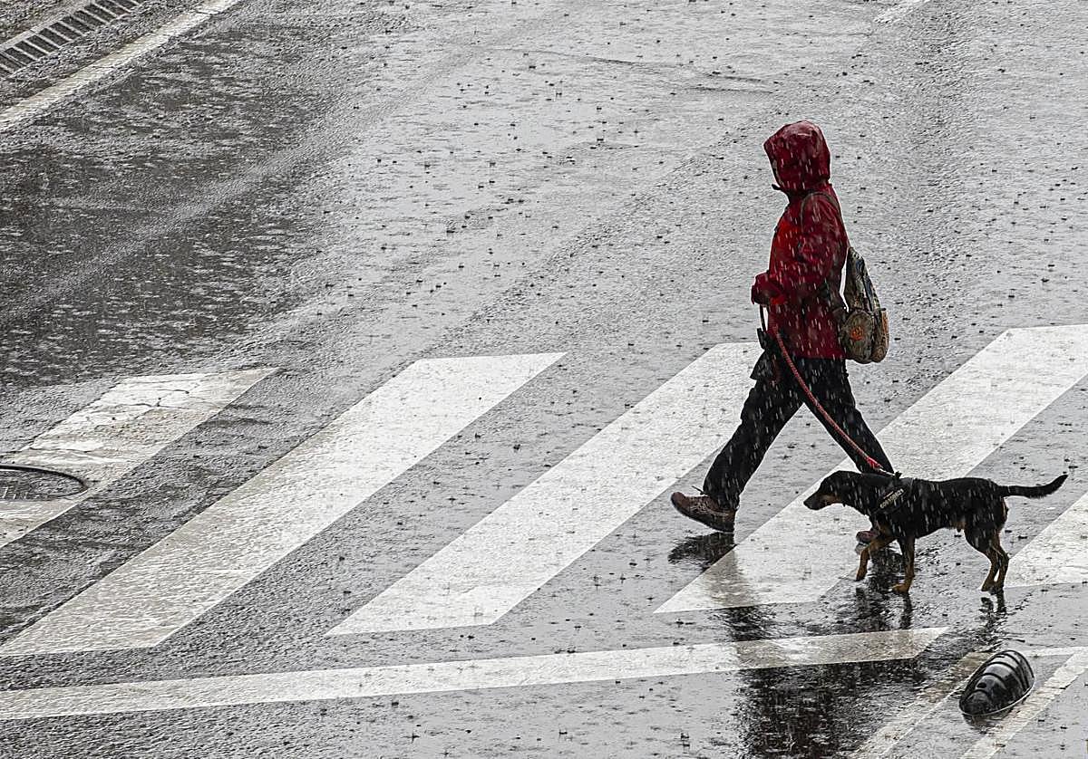 Una mujer cruza una calle durante una tormenta.