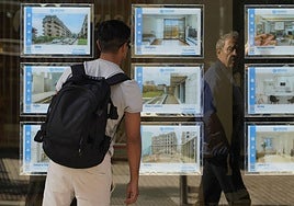 Un joven mira el escaparate de una inmobiliaria