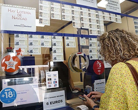 Una mujer compra lotería en una administracion.