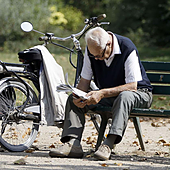 Un jubilado lee el periodico en un parque.