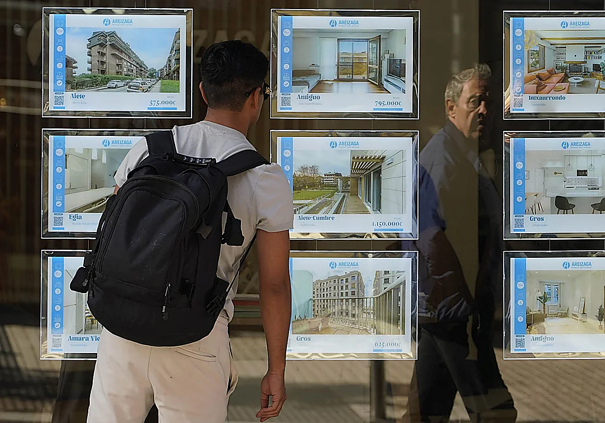 Un joven mira el escaparate de una inmobiliaria.