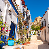 Una calle del barrio de Santa Cruz de Alicante, con el Castillo de Santa Bárbara al fondo