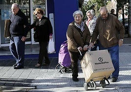 Dos personas mayores cargan una caja, en Valencia, en diciembre de 2019.