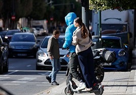 Dos jóvenes subidos sobre el mismo patín en un paso de peatones de la ciudad.