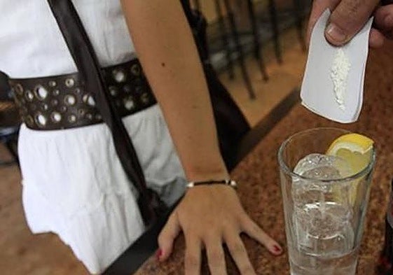 Simulación de un individuo echando droga en una bebida.