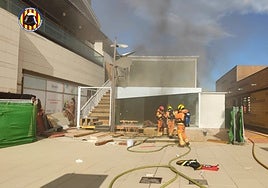 Un equipo de bomberos junto a la nave siniestrada.