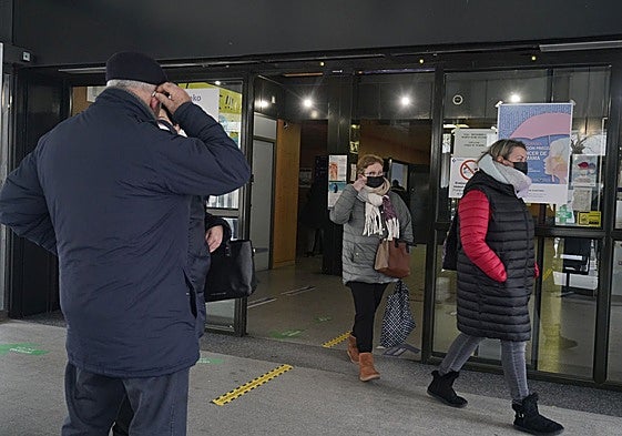 Varias personas con mascarilla salen de un centro de salud.
