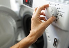 Una mujer programa una lavadora.