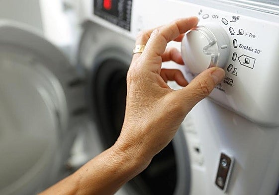 Una mujer programa una lavadora.