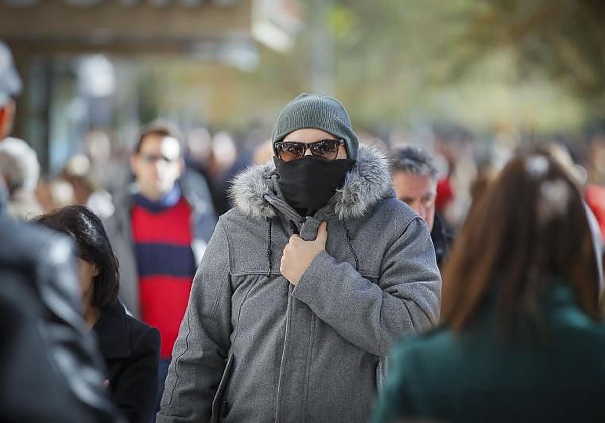 Un hombre se abriga del frío por la calle.