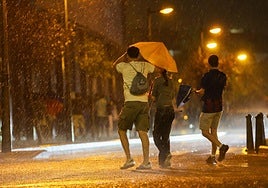 Una pareja se resguarda de las lluvias en Valencia.