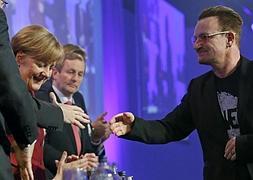 Bono, vocalista de la banda irlandesa U2, saluda a la canciller Merkel. / Juanjo Martín (Efe)