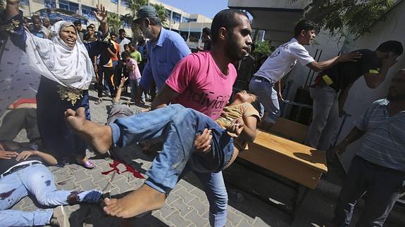 Un hombre transporta a un niño herido en el ataque.