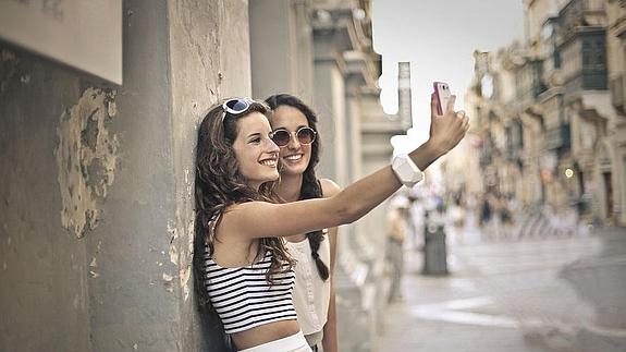 Dos chicas se toman una foto con el móvil. 