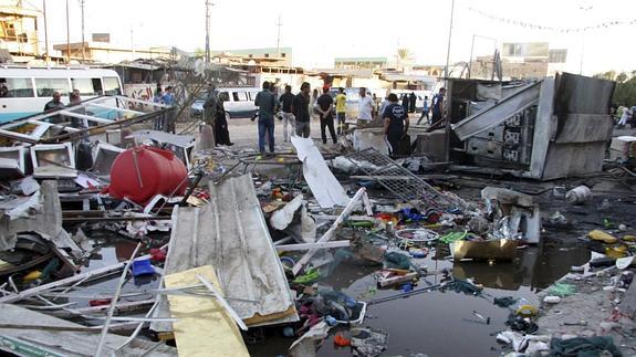 Varias personas observan los daños causados al explotar un coche bomba en Bagdad (Irak) 