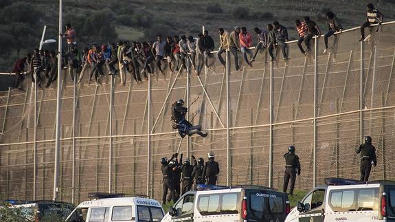 Inmigrantes saltando la valla de la frontera de Melilla con Marruecos. 