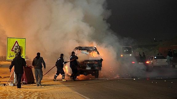 Varias personas tratan de apagar el incendio en un automóvil. 