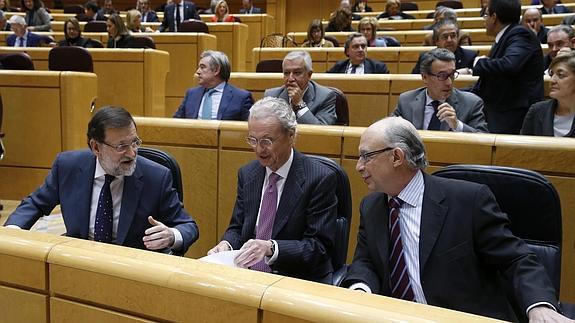 El ministro de Hacienda, Cristóbal Montoro (d), junto al presidente del Gobierno, Mariano Rajoy (i) y el ministro de Defensa, en el Senado.