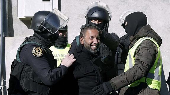 Agentes de la Guardia Civil trasladan a uno de los cuatro detenidos en una operación en la que se desarticuló una red de reclutamiento yihadista. 