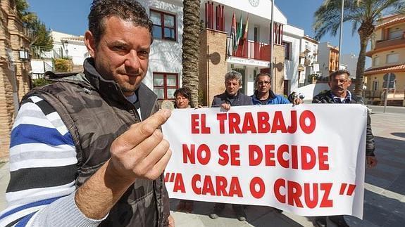 Juan José Gómez, protagonista en el sorteo, muestra una moneda delante de sus compañeros parados de protesta. 