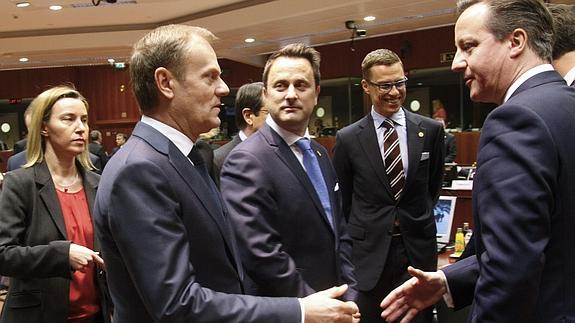 Donald Tusk saluda a David Cameron en presencia de Federica Mogherini. 