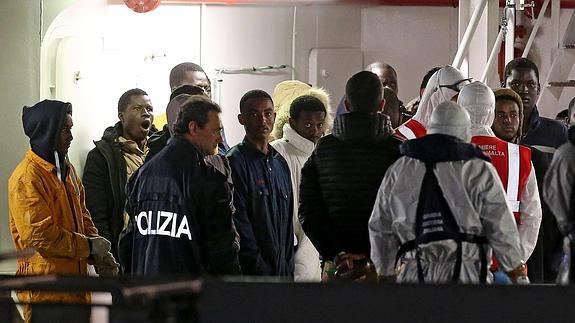 Policías guían a los inmigrantes supervivientes de los recientes naufragios en el puerto de Catania en Sicilia (Italia). 