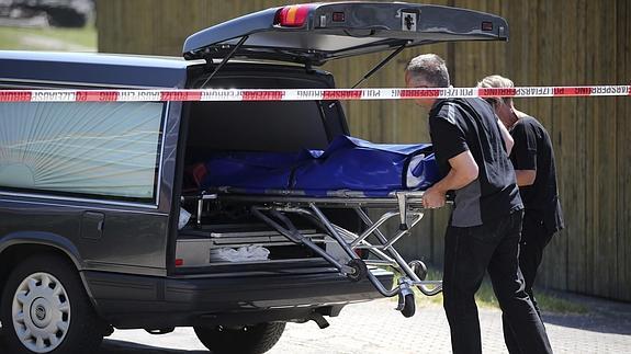 Empleados de una funeraria trasladan un cadáver desde la zona del tiroteo.