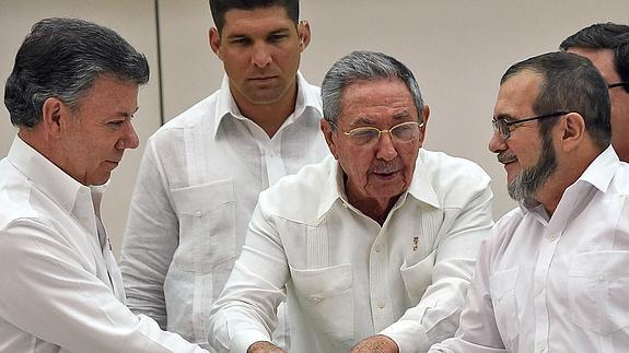 Juan Manuel Santos (i) y 'Timochenko' (d) se saludan en presencia de Raúl Castro.