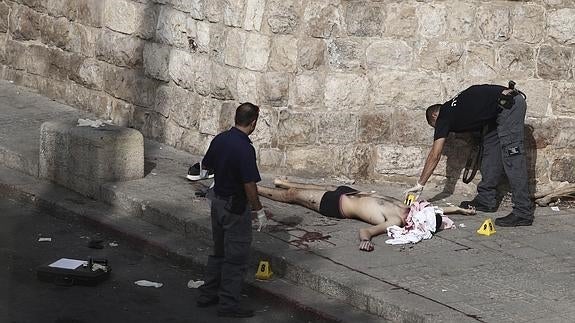 Un policía israelí inspecciona el cuerpo sin vida de un palestino en la Puerta de los Leones en Jerusalén (Israel).