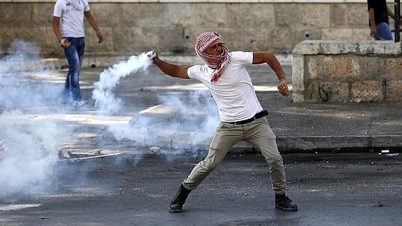 Un palestino arroja un bote de gas lacrimógeno en Belén.