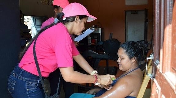 Una mujer embarazada recibiendo un spray antimosquitos. 