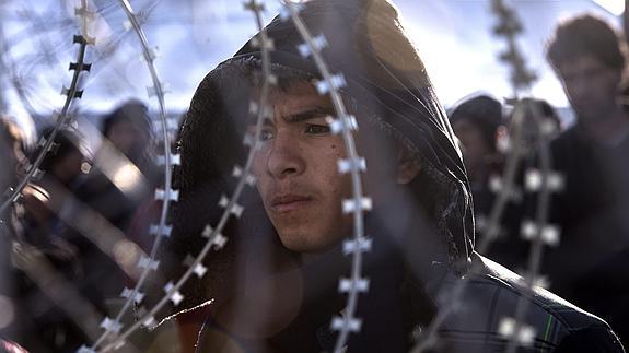 Un emigrante afgano permanece tras una alambrada de espino en la frontera entre Grecia y Macedonia.