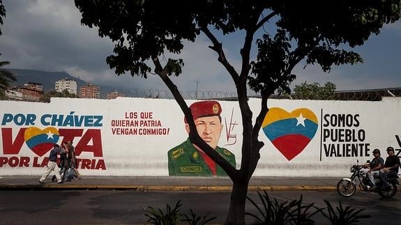 Personas pasan frente a un mural en honor del fallecido presidente venezolano Hugo Chávez.