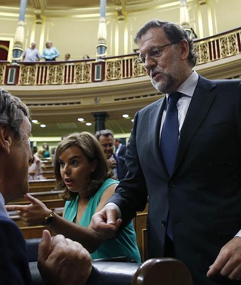 Rajoy conversa con el portavoz parlamentario del PP, Rafael Hernando, en presencia de la vicepresidenta. 