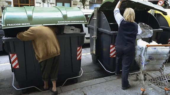 Una mujer busca comida en un contenedor.