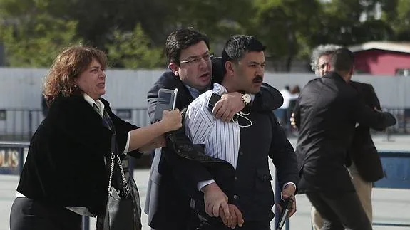 Un hombre agarra al presunto autor de los disparos en presencia de la mujer del periodista atacado. 