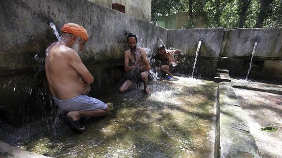 Tres hombres se refrescan en una fuente de la ciudad india de Amritsar.